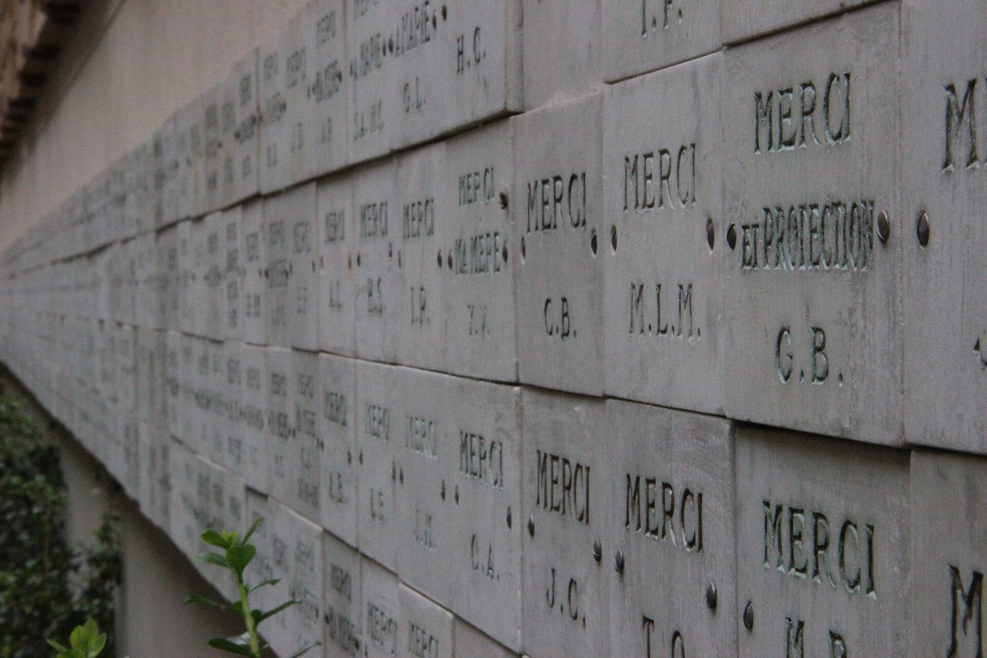 Bức tường treo các bia tạ ơn (ex-voto) khắc chữ “Merci” bên trong Nguyện đường Đức Mẹ Ảnh Phép Lạ